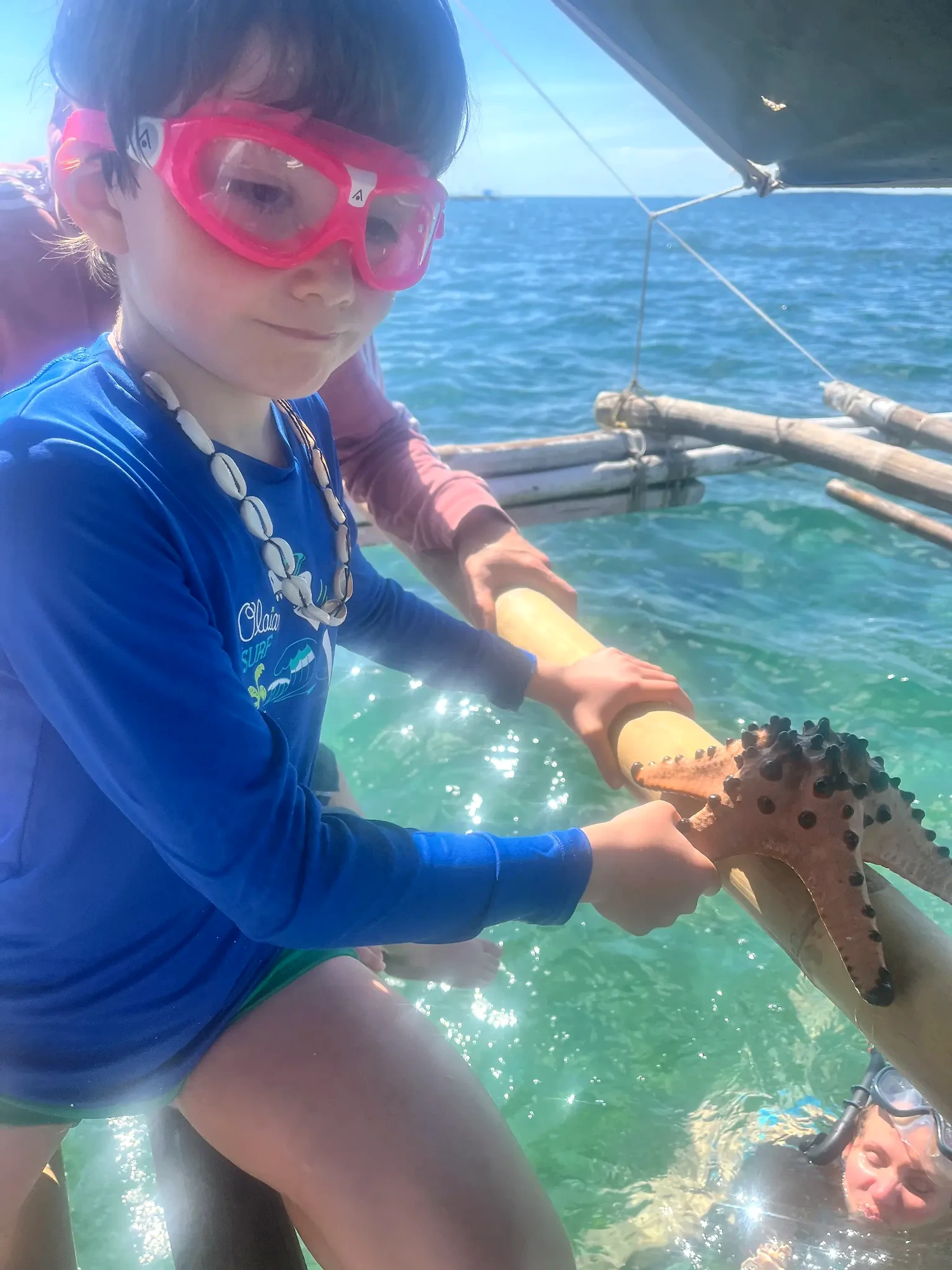 Child with a large starfish during an island hopping trip in Pilar Bay
