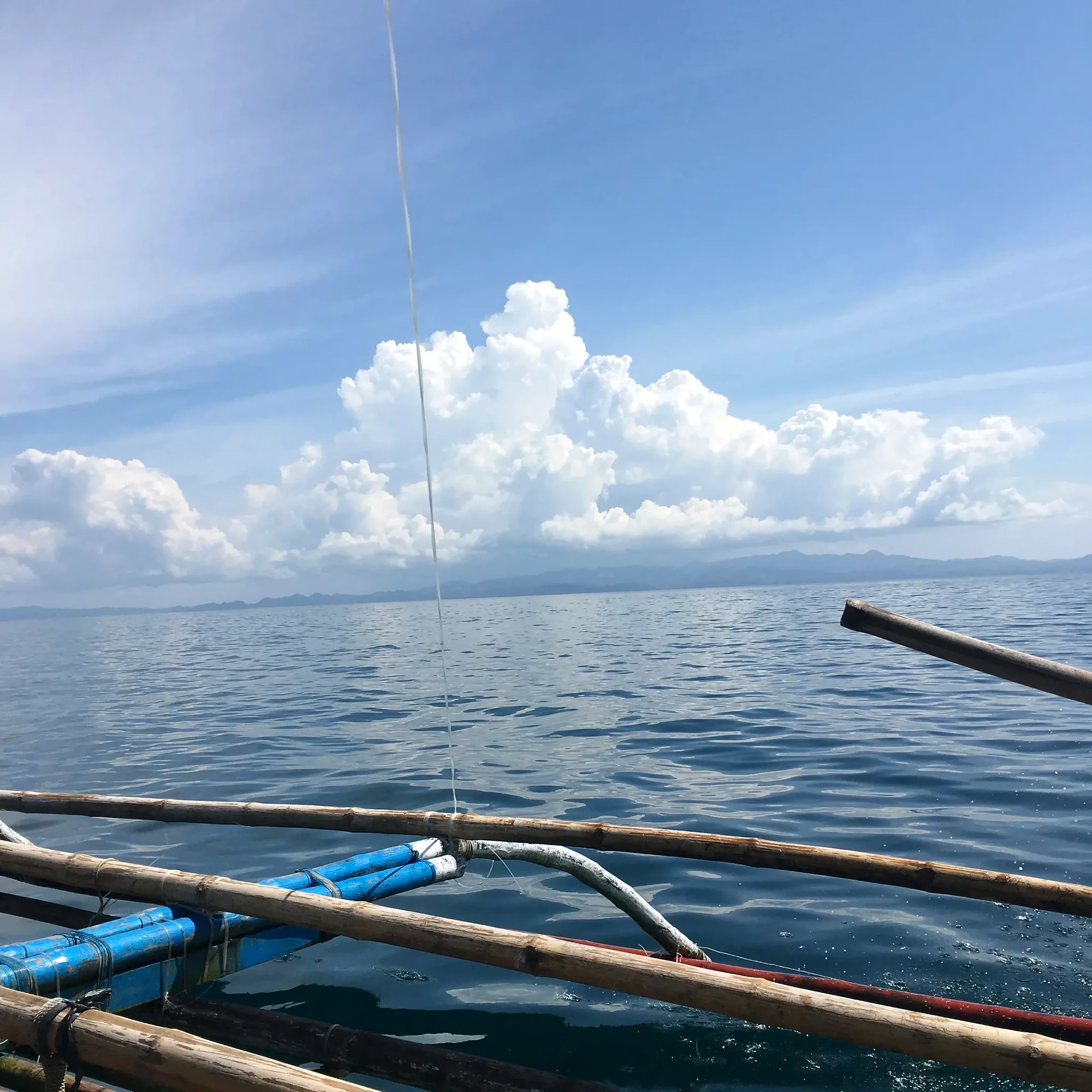 Bangka outriggers beneath large clouds over Pilar Bay, Sorsogon